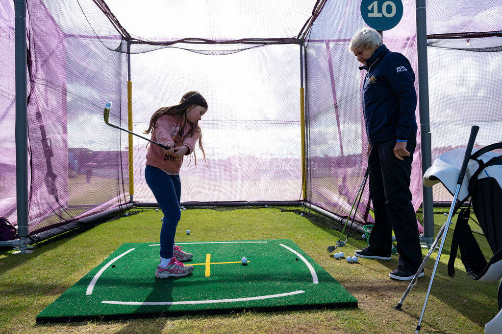 A young golfer practicing at the range at the AIG Women